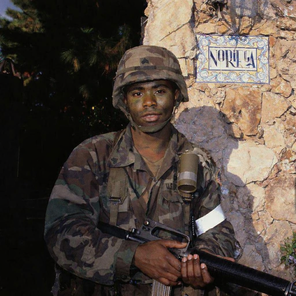solider in Panama in front of wall holding weapon